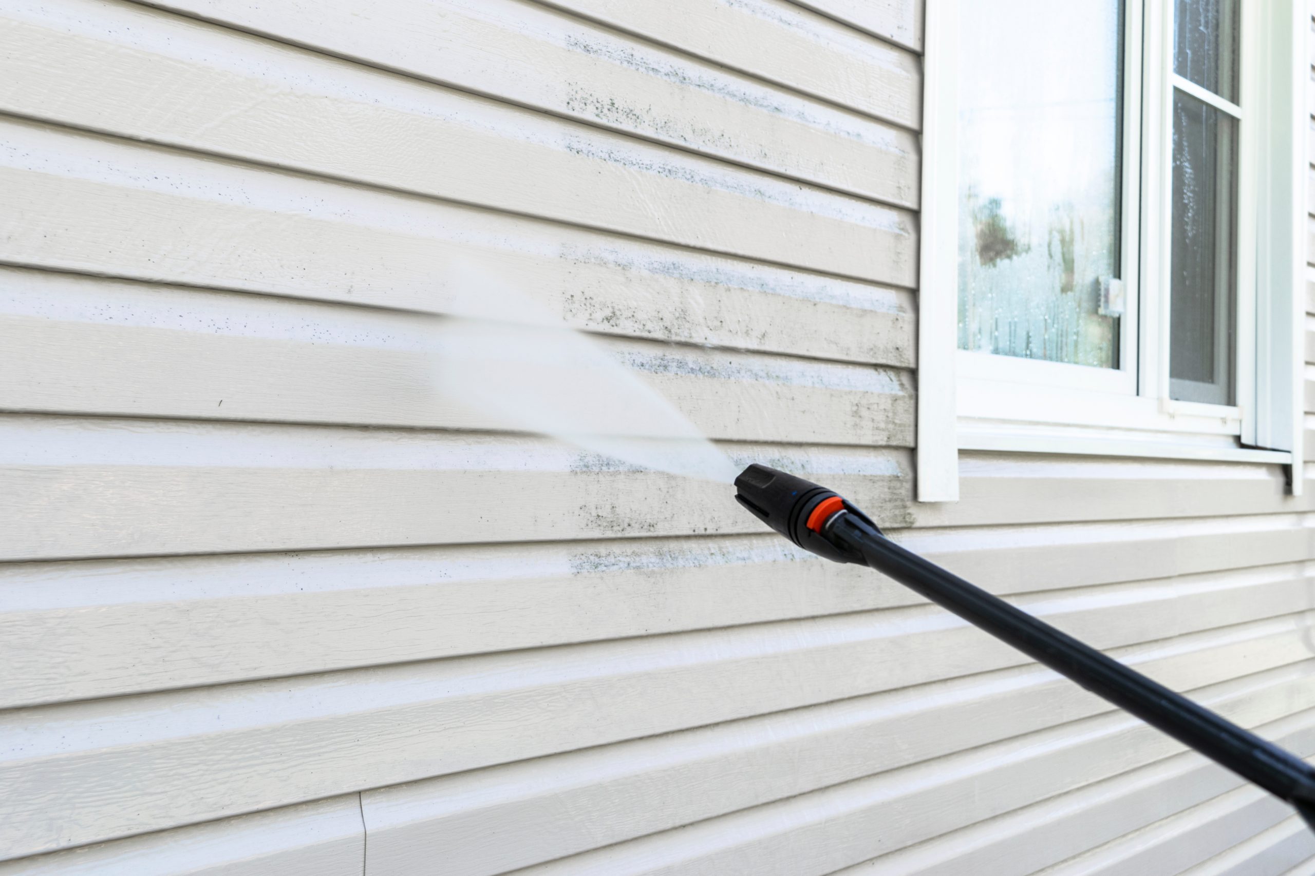 Pressure washing a house siding to remove dirt and grime in OKC